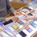 a man and a woman exchanging a cell phone at a store